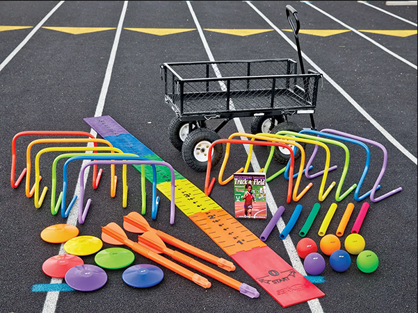 Colorful athletics training equipment arranged on a running track, including mini hurdles, cones, balls, batons, and a utility cart.